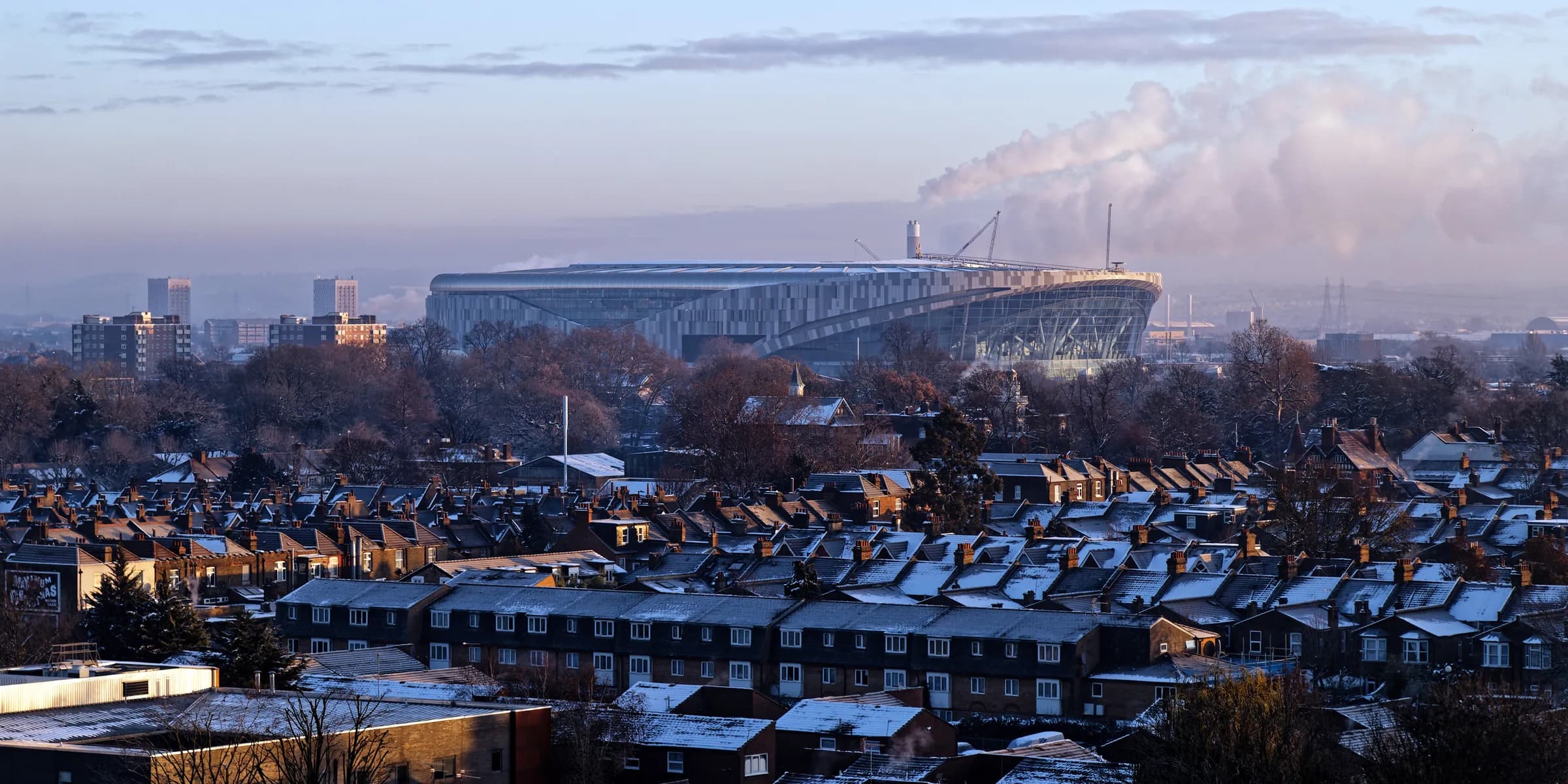 The Tottenham Hotspur Stadium rising above the terraced rooftops of Tottenham at dawn