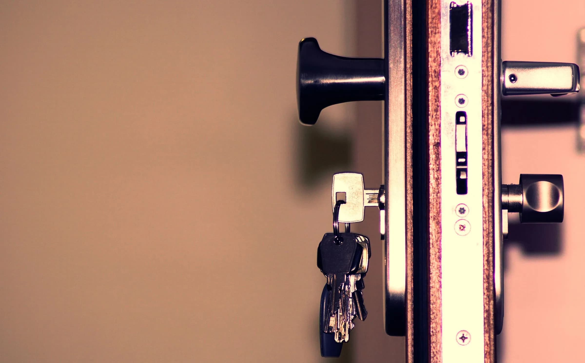 A bunch of keys hanging from a door lock, seen from the side.