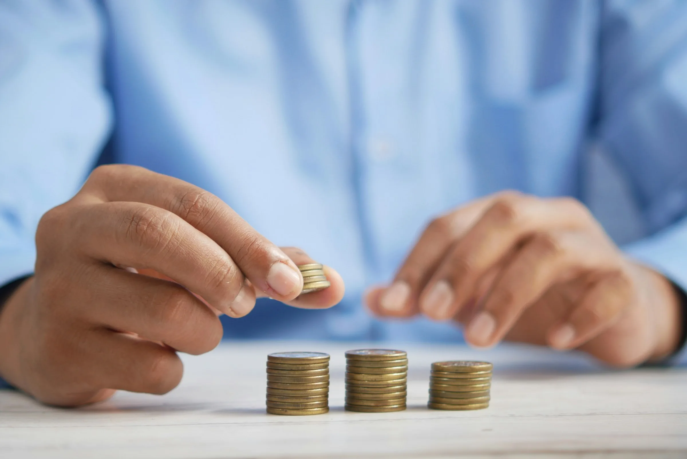A person stacking small coins into three piles on a table
