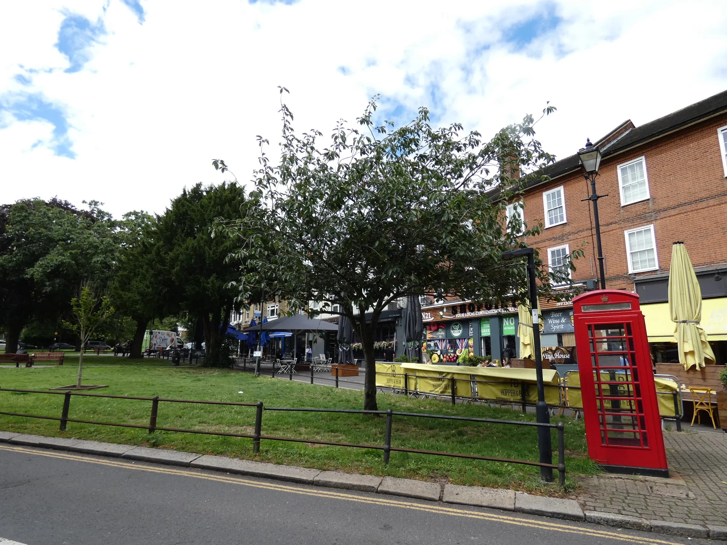 The Green at Winchmore Hill, with a red telephone box and the parade of shops behind